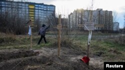 Dječak porolazi pord grobova sa tijelima civila koje su, prema navodima stanovnika, ubile ruske snage u Buči. (Foto: REUTERS/Vladyslav Musiienko)