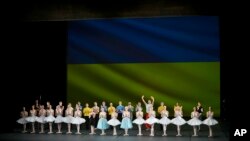 Ukrainian dancers of the Kyiv City Ballet company acknowledge applause in front of the Ukrainian flag. (AP Photo/Thibault Camus)