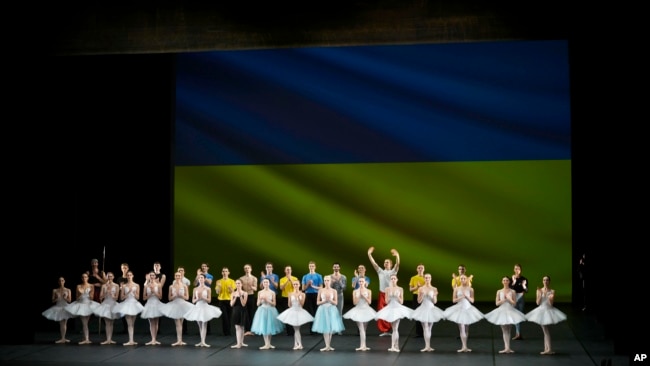 Ukrainian dancers of the Kyiv City Ballet company acknowledge applause in front of the Ukrainian flag. (AP Photo/Thibault Camus)