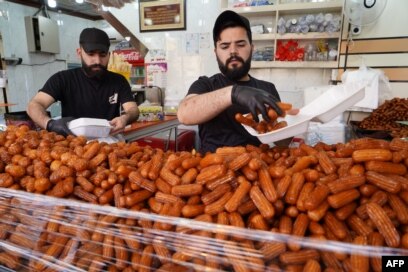 Penjual melayani pelanggan saat orang membeli permen pada hari pertama bulan puasa Ramadhan di kota utara Dohuk di wilayah otonomi Kurdi Irak, pada 2 April 2022. (Foto: AFP/Ismael Adnan)