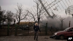 Associated Press videographer Mstyslav Chernov walks amid smoke rising from an air defense base in the aftermath of a Russian strike in Mariupol, Ukraine, Feb. 24, 2022.