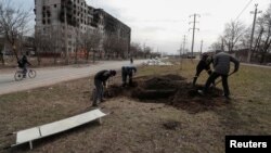 Ljudi kopaju grob za žrtve ubijene u opkoljenom južnom lučkom gradu Mariupolju, Ukrajina 20. marta 2022. REUTERS/Alexander Ermochenko