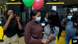 South African student Vutlhari Mtonga, center-left, who was evacuated from Ukraine following Russia's invasion of the country, is welcomed by her sister Mikateko Mtonga, on arrival at OR Tambo International Airport, in Johannesburg, South Africa, March 10