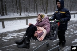 Stariju ženu nose u kolicima za kupovinu nakon evakuacije iz Irpina, na periferiji Kijeva, u Ukrajini, u utorak, 8. marta 2022.
