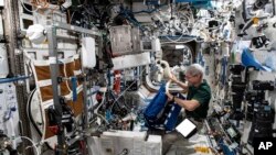 Astronaut AS Mark Vande Hei tengah menyusun sepeda latihan di dalam Stasiun Luar Angkasa Internasional, pada 22 Juni 2021. (Foto: NASA via AP)