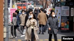 Orang-orang yang memakai masker berjalan di sebuah distrik perbelanjaan di tengah pandemi COVID-19 di Seoul, Korea Selatan, 16 Maret 2022. (Foto: Reuters)