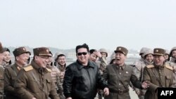 This picture released by North Korea's official Korean Central News Agency shows North Korean leader Kim Jong Un (C) walking with military personnel during the test of what state media reports is a new inter-continental ballistic missile at an undisclosed