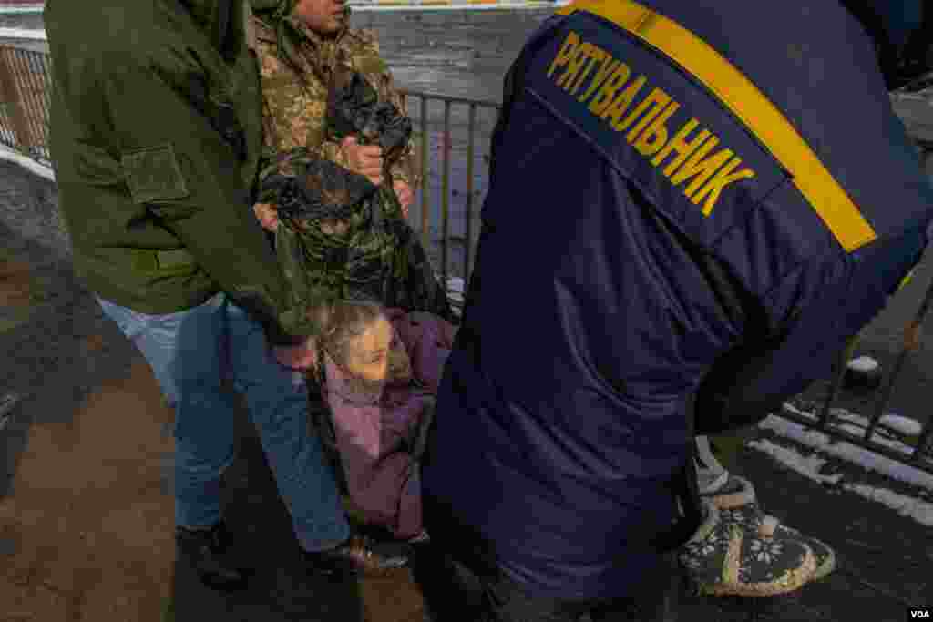 Civilians and soldiers used an improvised hammock to extract an elderly woman, in Irpin, Ukraine, March 8, 2022. (Yan Boechat/VOA) 