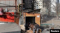 ရုရှားစစ်တပ် တိုက်ခိုက်မှုကြောင့် ပျက်စီးသွားတဲ့ နေအိမ်အဆောက်အအုံ အပြင်ဘက်မှာ ချက်ပြုတ်စားသောက် နေထိုင်နေရတဲ့ Mariupol မြို့ခံအချို့။ (မတ် ၃၁၊ ၂၀၂၂)