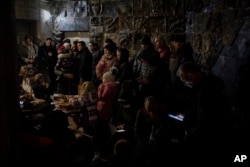 People gather in a basement, used as a bomb shelter, during an air raid in Lviv, western Ukraine, March 19, 2022.