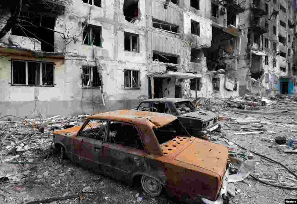 Los restos de autos se ven frente a un edificio de apartamentos destruido.