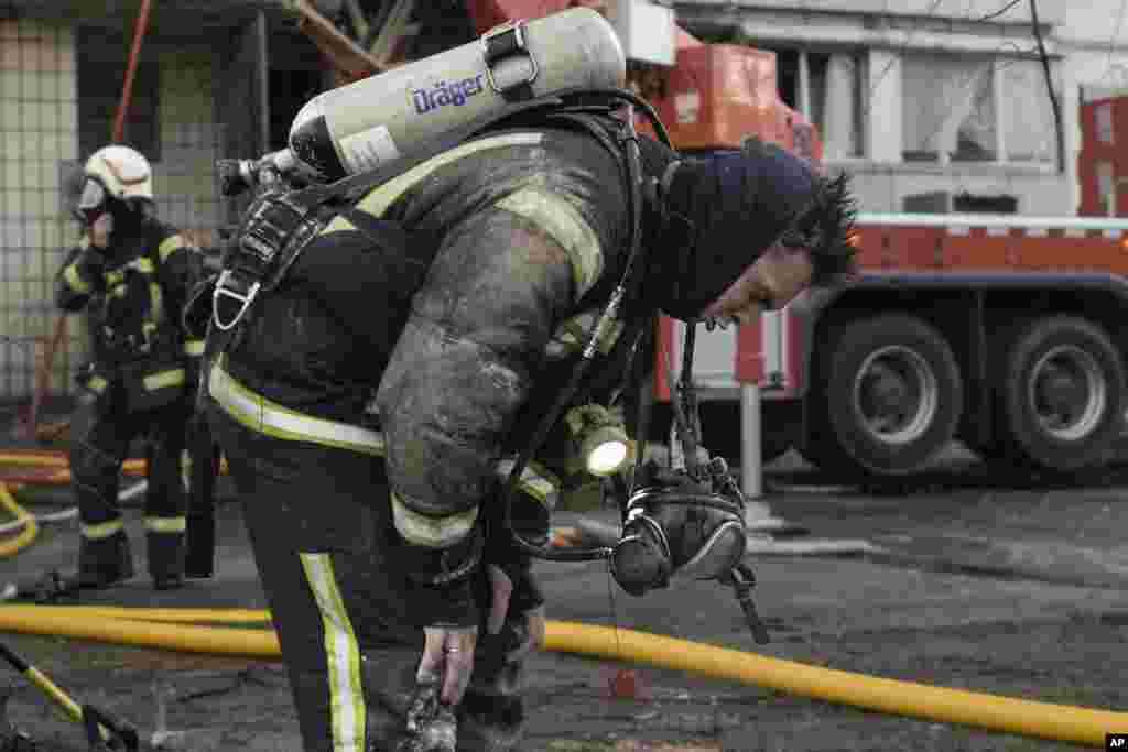 A firefighter catches his breath after exiting a destroyed apartment building following a bombing in a residential area in Kyiv, March 15, 2022.