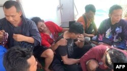 Pekerja migran asal Indonesia tampak terduduk lemas di kapal milik tim SAR setelah berhasil diselamatkan dari laut di Sumatra Utara ketika feri yang mereka tumpangi tenggelam pada 19 Maret 2022. Feri tersebut hendak bergerak menuju Malaysia. (Foto: Handout/Search and Rescue/AFP)