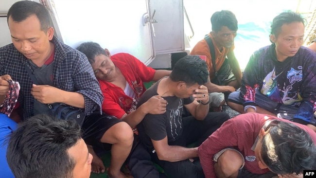 Para pekerja migran asal Indonesia tampak terduduk lemas di kapal milik tim SAR setelah sebelumnya berhasil diselamatkan dari laut di Sumatra Utara ketika feri yang mereka tumpangi tenggelam pada 19 Maret 2022.