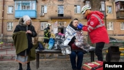 FILE - A paramedic helps a woman injured at the site of a residential district after it was hit by shelling, in Kyiv, Ukraine, March 18, 2022. Doctors in the U.S. are using telemedicine to provide advice to Ukranians hurt in the fighting or attempting to manage chronic diseases. 