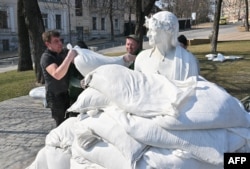 City workers cover a monument to Italian poet, writer and philosopher Dante Alighieri with sandbags to protect it against Russian shelling, in Kyiv, Ukraine, March 23, 2022.