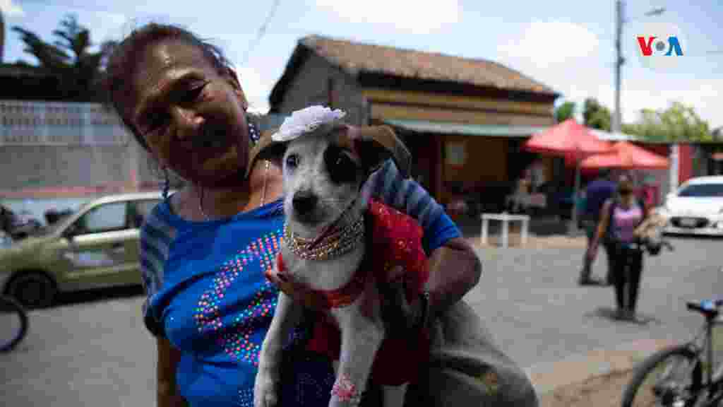 Una señora muestra su mascota previo a ingresarla a la iglesia.