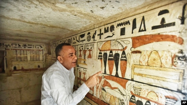 Mostafa Waziri, secretary general of the Supreme Council of Antiquities, views hieroglyphics inside a recently discovered tomb near the famed Step Pyramid, in Saqqara, south of Cairo, Egypt, March 19, 2022.