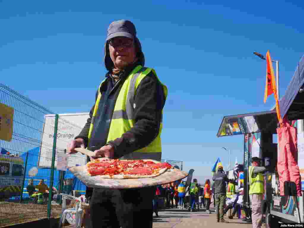 Los voluntarios proveen a los refugiados con distintos tipos de alimentos. En la imagen, uno de ellos reparte una pizza recién cocinada.