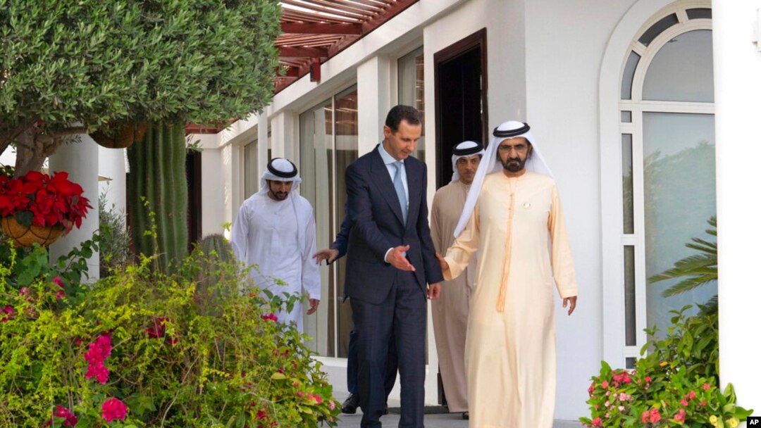 In this photo released by the Facebook page of the Syrian presidency, Syrian President Bashar al-Assad, left, walks next to Sheikh Mohammed bin Rashid Al Maktoum, vice president and prime minister of the UAE and the ruler of Dubai, in Dubai, United Arab Emirates, March 18, 2022.