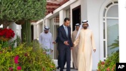 In this photo released by the Facebook page of the Syrian presidency, Syrian President Bashar al-Assad, left, walks next to Sheikh Mohammed bin Rashid Al Maktoum, vice president and prime minister of the UAE and the ruler of Dubai, in Dubai, United Arab Emirates, March 18, 2022.