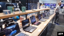 FILE - A vendor stands next to laptops displayed in Technopark home electronics shop in Moscow, Feb. 25, 2022.