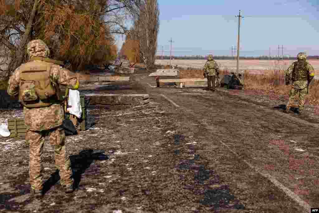 Ukrainian servicemen stand guard at a check point near the village of Velyka Dymerka, 40 km east of Kyiv, March 10, 2022.
