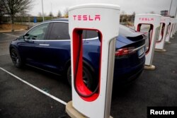 Seorang pengemudi mengisi ulang baterai mobil Tesla-nya di stasiun Pengisian Super Tesla di sebuah pompa bensin di jalan raya Sailly-Flibeaucourt, Prancis, 12 Januari 2019. (REUTERS/Pascal Rossignol)