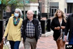 Paula and Ed Kassig, left, the parents of Peter Kassig, walk alongside Bethany Haines, second right, the daughter of David Haines, as they return to the Alexandria federal courthouse after a break for the trial of IS member El Shafee Elsheikh in Alexandria, Virginia, March 30, 2022.