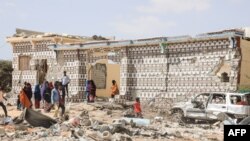FILE: People walk next to a destroyed house and the wreckage of a car following an explosion provocked by Al-Shabaab militants' during an attacke to a police station on the outskirts of Mogadishu, Somalia. Taken 2.16.2022