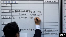 FILE - Workers of the Japan Council of Metalworkers' Union check the results of wage negotiations, at its headquarters in Tokyo, March 16, 2016. 