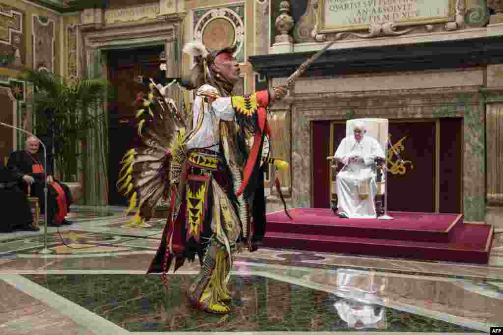 A member of Canada&#39;s Indigenous delegations dances in front of Pope Francis at the Vatican. Pope Francis apologized for many years of abuse at church-operated schools in Canada, and said he would visit the country in late July. (Vatican Media / AFP)