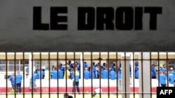 Des détenus à la prison de Makala à Kinshasa, en République Démocratique du Congo, le 18 décembre 2012, derrière les barreaux des fenêtres d'une salle d'audience. (Photo AFP/ Junior D. Kannah)