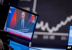 资料照片：德国法兰克福股票市场的一个电视屏幕播放着俄罗斯总统普京的镜头。屏幕下方的字幕写道：“网上与电视上的宣传战” 。(2022年2月25日)