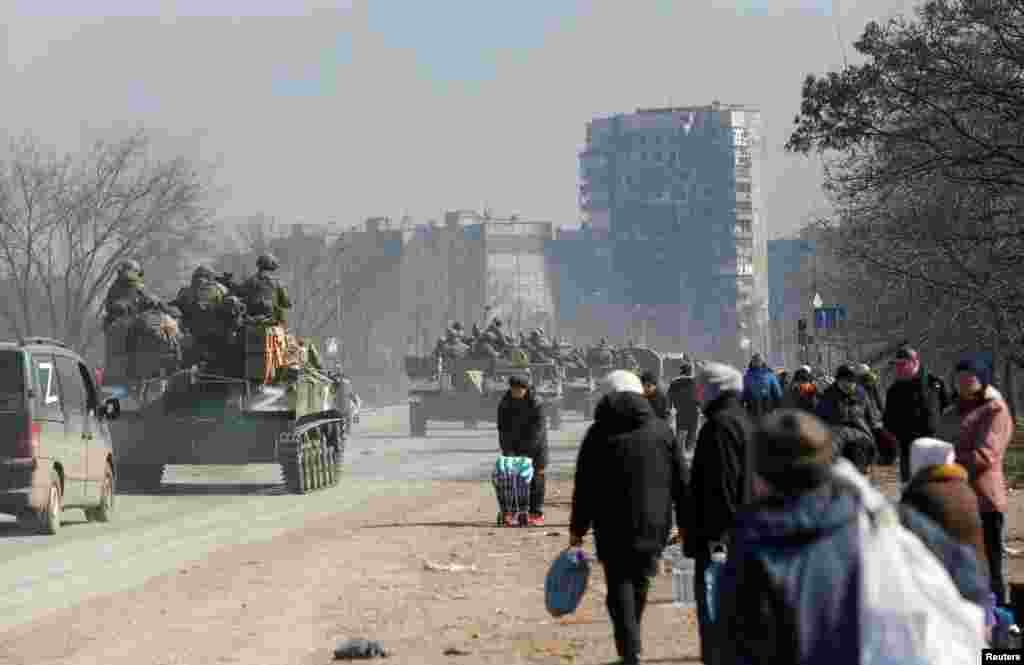 Miembros del servicio de las tropas prorrusas conducen vehículos blindados frente a los residentes locales en el curso del conflicto entre Ucrania y Rusia en la ciudad portuaria sitiada del sur de Mariúpol, Ucrania, el 24 de marzo de 2022.