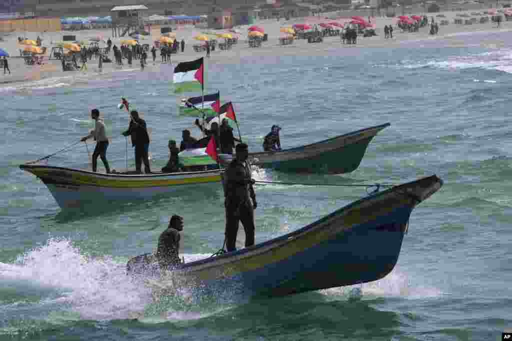 Palestinian fishermen ride their boats while wave their national flags during a rally marking the 46th anniversary of Land Day, in the Mediterranean Sea at the fishermen port in Gaza City.