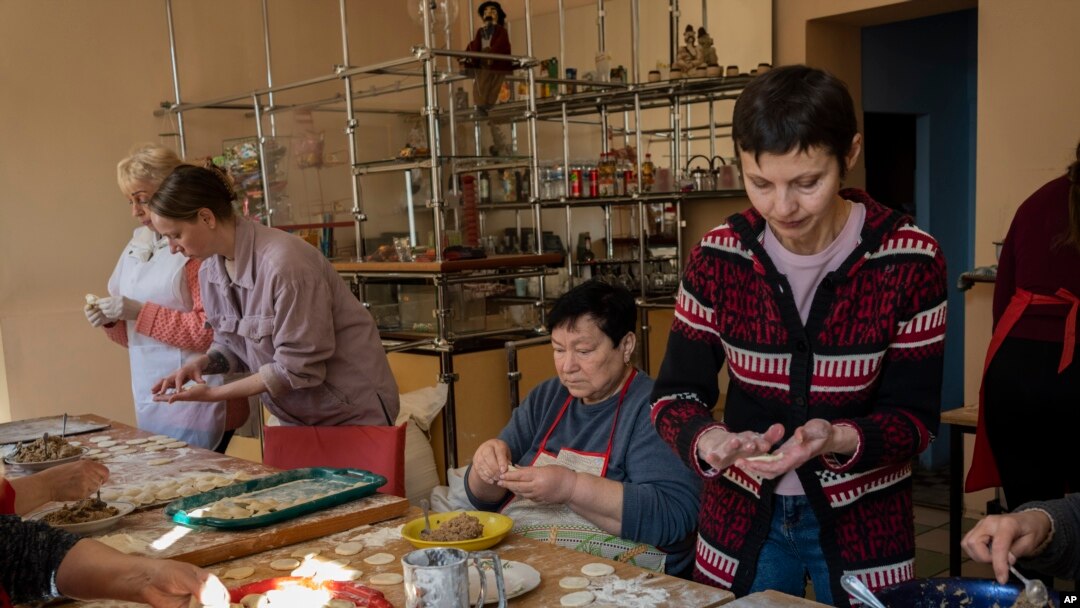 Relawan memasak varenyky, pangsit isi, di dalam teater di kota Drohobych, Ukraina barat, Senin, 21 Maret 2022. Teater itu menjadi titik pertemuan, tempat para seniman dan pengungsi dari bagian lain Ukraina untuk membuat makanan bagi tentara dan lainnya. (AP / Bernat Armangue)