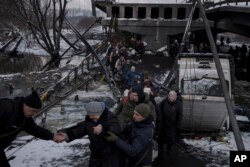 Warga Ukraina melintasi jalur improvisasi di bawah jembatan yang hancur saat melarikan diri dari Irpin, di pinggiran Kyiv, Ukraina, Selasa, 8 Maret 2022. (Foto: AP/Felipe Dana)