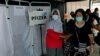 Seorang perempuan membantu lansia yang baru saja disuntik booster dengan vaksin Pfizer di tengah meningkatnya varian Omicron di Jakarta, 12 Januari 2022. (REUTERS/Willy Kurniawan)