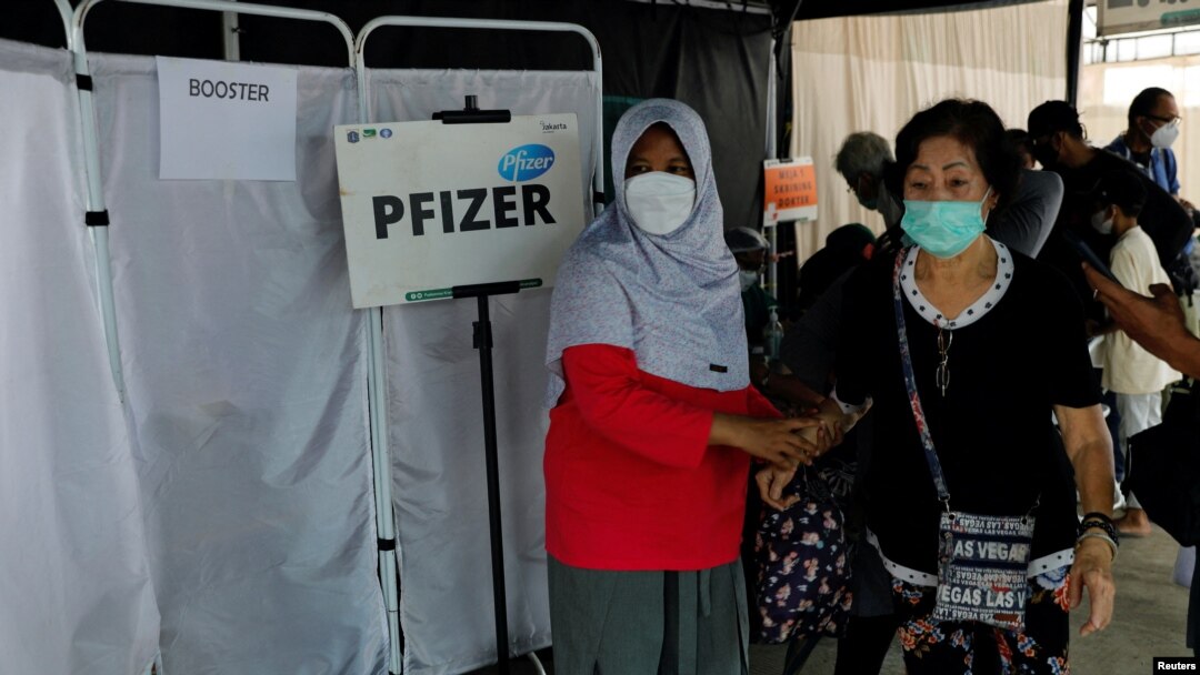 Seorang perempuan membantu lansia yang baru saja disuntik booster dengan vaksin Pfizer di tengah meningkatnya varian Omicron di Jakarta, 12 Januari 2022. (REUTERS/Willy Kurniawan)
