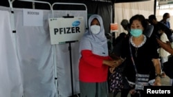 Seorang perempuan membantu lansia yang baru saja disuntik booster dengan vaksin Pfizer di tengah meningkatnya varian Omicron di Jakarta, 12 Januari 2022. (REUTERS/Willy Kurniawan)