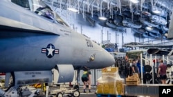 Servicemen exercise next to a Boeing E/A 18-G Growler aircraft inside the USS Harry S. Truman carrier cruising in the Mediterranean Sea, March 17, 2022.