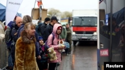 Ukrainian refugees fleeing Russia's invasion of Ukraine wait to a board a bus, bound for Przemysl, after crossing the Ukraine-Poland border, in Medyka, Poland, April 1, 2022.