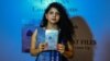 FILE - Indian journalist and author, Rana Ayyub poses with her self published book 'Gujarat Files' during the launch event in New Delhi, May 27, 2016.