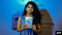 FILE - Indian journalist and author, Rana Ayyub poses with her self published book 'Gujarat Files' during the launch event in New Delhi, May 27, 2016.