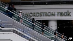 Para pengunjung Nordstrom Local DTLA di pusat kota Los Angeles, mengenakan masker saat mereka berbelanja di kawasan tersebut, Selasa, 15 Maret 2022. (AP/Damian Dovarganes)