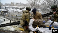 Ukrainian soldiers carry a wounded woman during the evacuation by civilians of the city of Irpin, northwest of Kyiv, March 8, 2022.