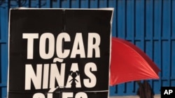 En esta foto del 4 de noviembre de 2019, una mujer sostiene una pancarta que dice: "tocar niñas si es un delito" durante una protesta en San Salvador, El Salvador.