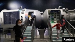 FILE - Visitors walk near a model of a space laboratory at an exhibition featuring the development of China's space exploration, on the country's Space Day at the China Science and Technology Museum in Beijing, April 24, 2021.