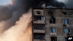 An elderly resident waits to be rescued by Ukrainian firefighters after bombing in an apartment building in Kyiv, Ukraine, Tuesday, March 15, 2022. (AP Photo/Felipe Dana)